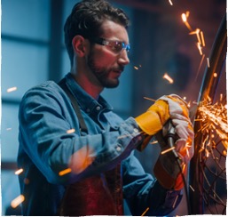 A metalworker shaping material with a grinder